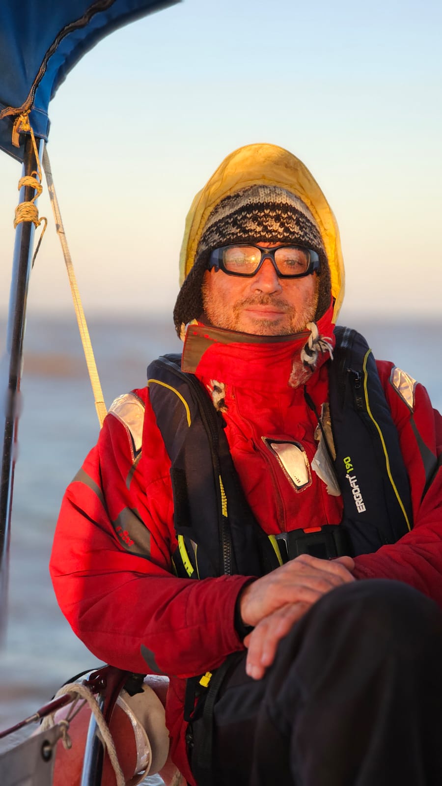 Guillermo con capucha amarilla y ropa de agua roja, al atardecer
